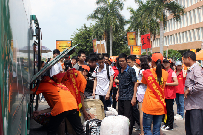 又一批从车站刚接回来的新生和家长,志愿者正忙着为他们卸下行李
